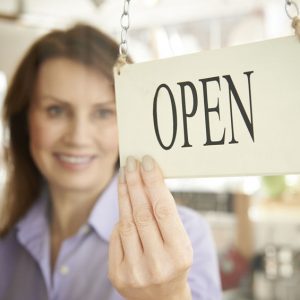 Store Owner Turning Open Sign In Shop Doorway