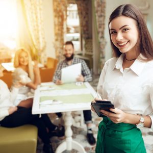 Portrait beautiful young waitress standing in cafe. Female waitress taking order at restaurant. Beatifull girl preparing bill at cafe. Waiter serving, restaurant service, small business owner concept.